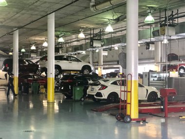 Onarım için kaldırma platformu üzerinde bir araba tamir dükkanında Araçlar. Arka planda özel tamir ekipmanları ile oto tamir servisi dükkanı için garajda Arabalar.