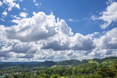 Bulutlar ve gökyüzü ile küçük bir kasaba olan dağ