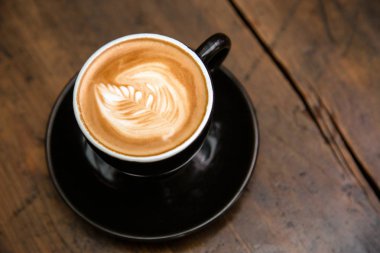 Ahşap masa arkasında bir fincan kahve.