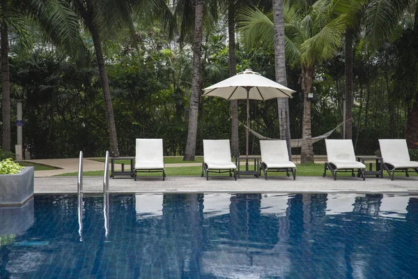 Sillas de playa y sombrilla junto a la piscina — Foto de Stock