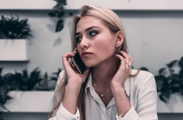 cute blonde woman speaks on the phone indoors cafe