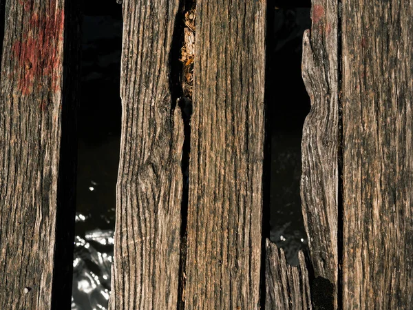 Old worn out and broken wood boards on a bridge over a small river