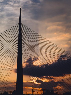 Gün batımında - yapraklara arka planda bulutların arasından büyük Asma Köprüsü Kulesi