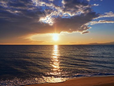 Sahilde - yapraklara Bulutların arasından parlayan güzel ve sakin günbatımı