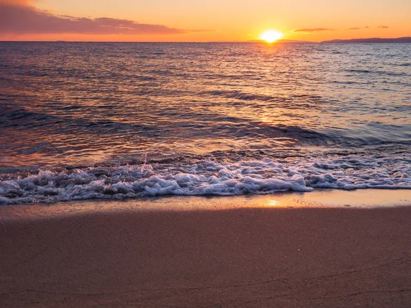 Güzel bir boş kumlu plajda gün batımı - köpüklü dalgalar