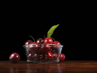 Ahşap bir masanın üstündeki cam kasede taze kırmızı kirazlar.