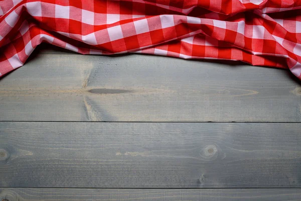 A checked gingham picnic tablecloth on old wooden table top view — Stock Photo, Image