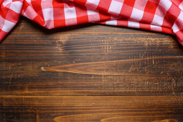 Une nappe de pique-nique à carreaux gingham sur une vieille table en bois vue sur le dessus — Photo