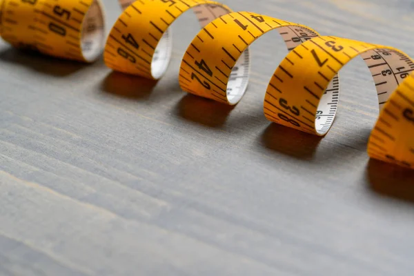 Yellow Tailor measuring tape on wooden table back — Stock Photo, Image