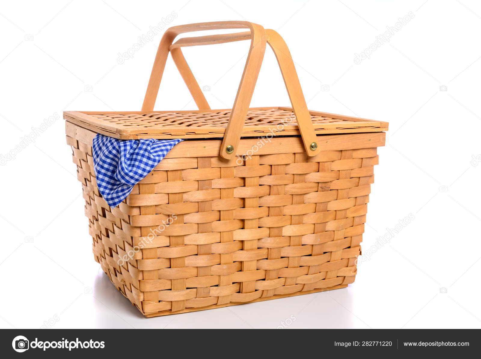 A brown wicker picnic basket on a white background with gingham cloth