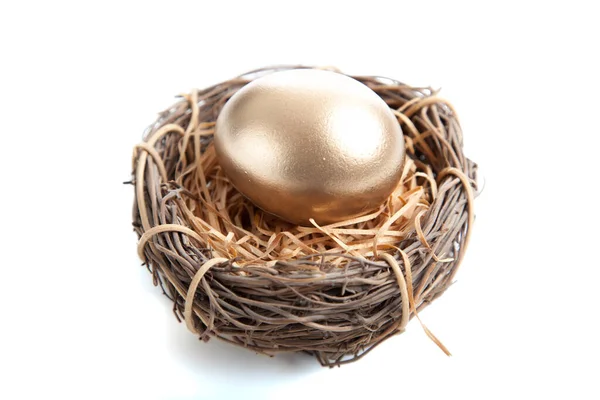 Złote jajko w gnieździe na białym tle — Zdjęcie stockowe