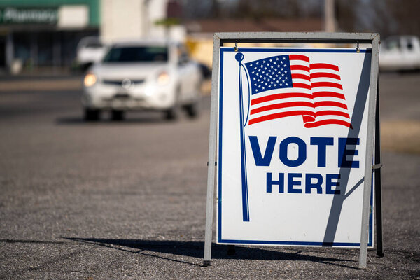 A Vote Here sign in a parking lot. High quality photo