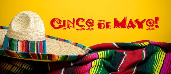 Coperta messicana Serape e sombrero su sfondo giallo con Cinco de Mayo. — Foto Stock