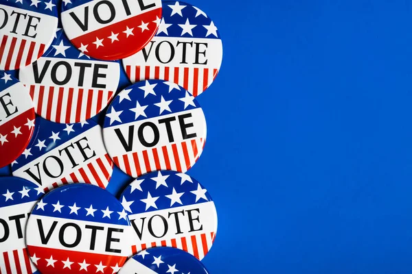 Bir grup kırmızı, beyaz ve mavi VOTE düğmesi mavi arkaplan üzerinde — Stok fotoğraf