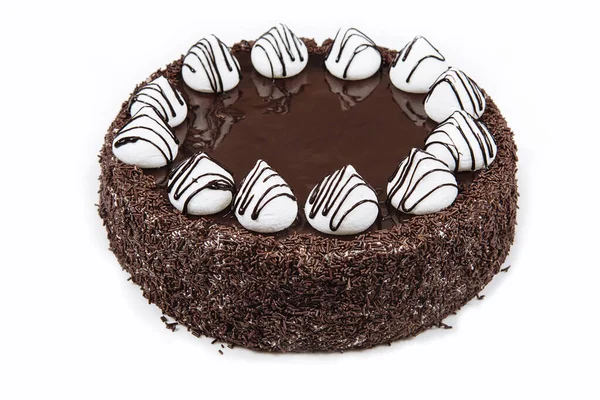 Chocolate cake with meringue. Cake is covered with chocolate chips and chocolate icing, decorated with meringue. View from above. Birthday or holiday. Pastry.
