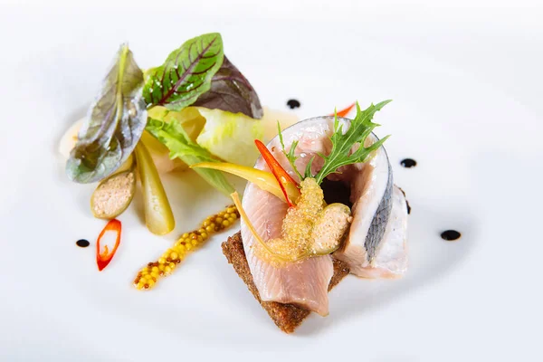 Salad or appetizer of salted fish with spices, herbs, on toasted rye bread, with capers, caviar, mustard and mashed potatoes on white background. Pickled herring.