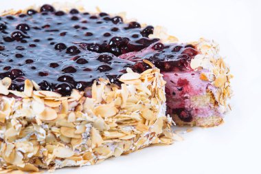 Sponge cake with berries, butter cream, covered with fruit glaze and nut chips stands on white background. Birthday or holiday. Confectionery.