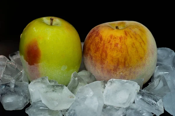 Фото танення заморожених яблук серед кубиків льоду крупним планом на чорному тлі — стокове фото