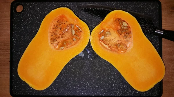 photo of a cut pear-shaped pumpkin with seeds on a black board