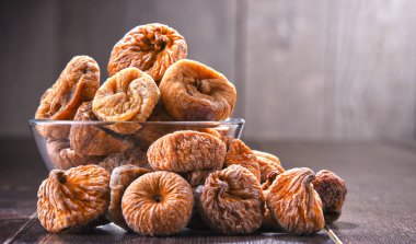 Ahşap masada bir kase kurutulmuş incir ile kompozisyon.