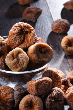 Ahşap masada bir kase kurutulmuş incir ile kompozisyon.