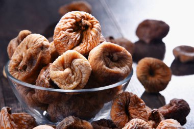 Ahşap masada bir kase kurutulmuş incir ile kompozisyon.