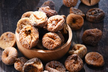 Ahşap masada bir kase kurutulmuş incir ile kompozisyon.