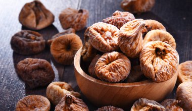 Ahşap masada bir kase kurutulmuş incir ile kompozisyon.