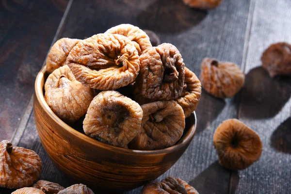 Ahşap masada bir kase kurutulmuş incir ile kompozisyon.