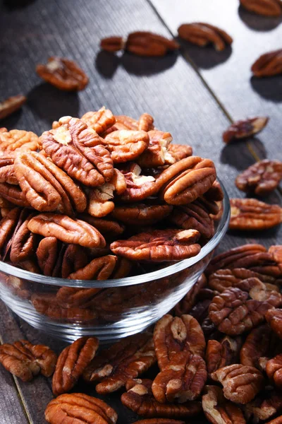 Bowl with pecan nuts on wooden table. Delicacies