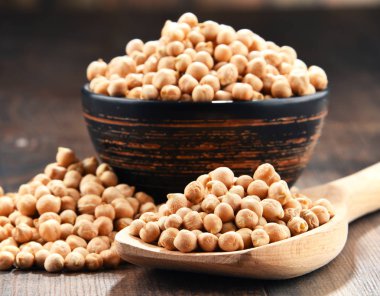 Ahşap masada bir kase nohut ile kompozisyon.