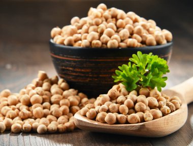 Ahşap masada bir kase nohut ile kompozisyon.