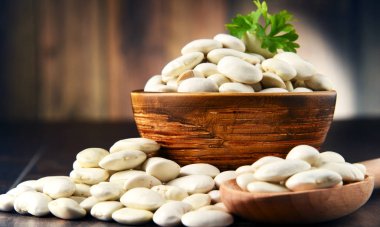 Tahta masanın üzerinde bir kase beyaz fasulye ile kompozisyon.