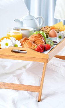 Otel odasında yatakta kahvaltı tepsisi. 