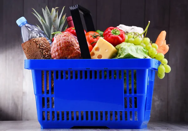 Plastic shopping basket with assorted grocery products.