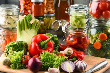 Kavanoz ile marine edilmiş yiyecek ve çiğ sebze kesme tahtası üzerinde.