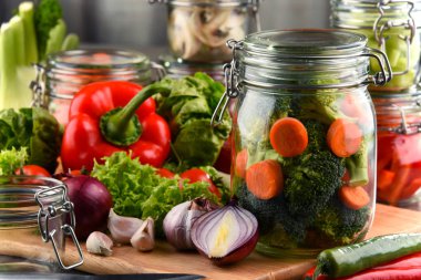 Kavanoz ile marine edilmiş yiyecek ve çiğ sebze kesme tahtası üzerinde.