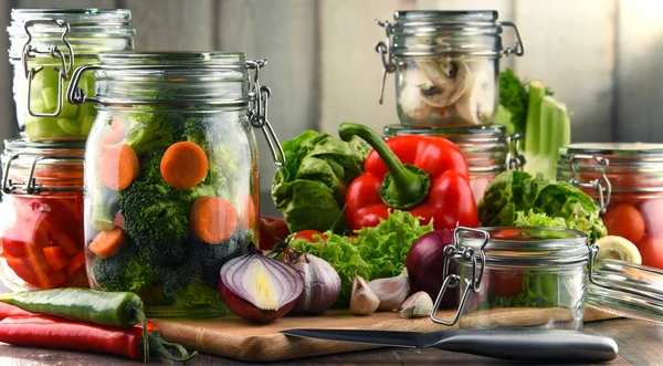 Gläser Mit Mariniertem Essen Und Rohem Gemüse Auf Schneidebrett — Stockfoto