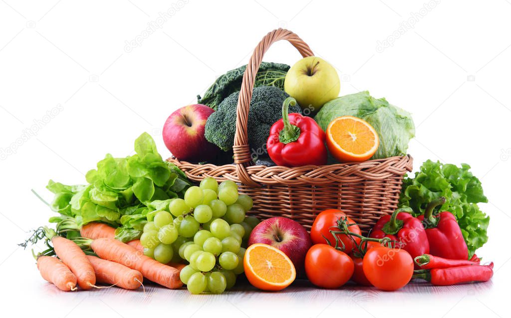 Fresh organic fruits and vegetables in wicker basket isolated on white