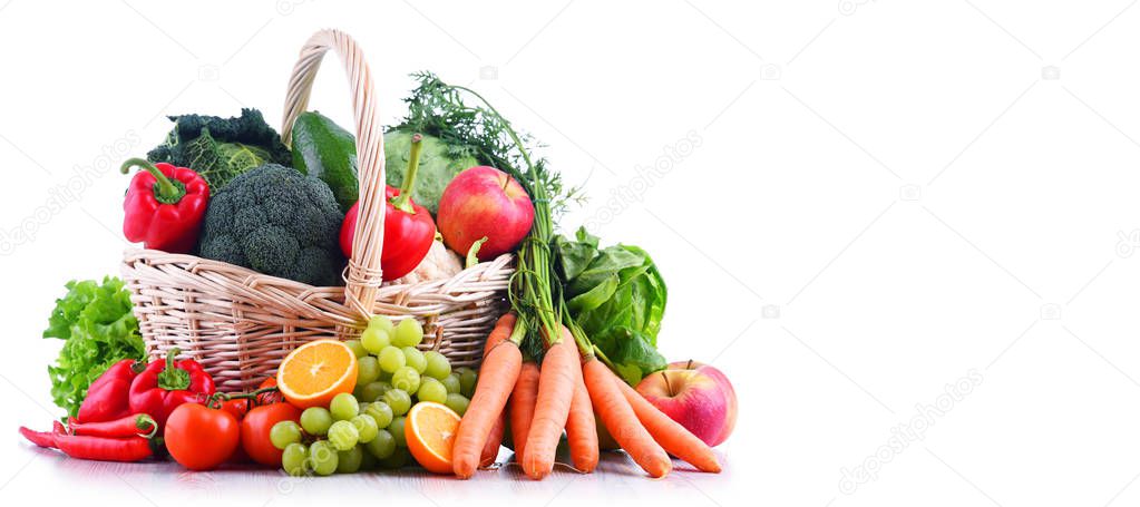 Fresh organic fruits and vegetables in wicker basket isolated on white