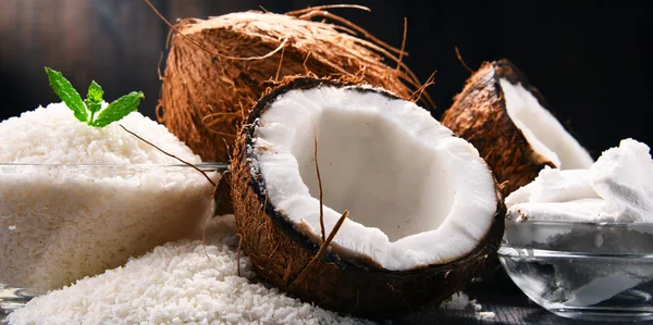 Composition with bowl of shredded coconut and shells on wooden table