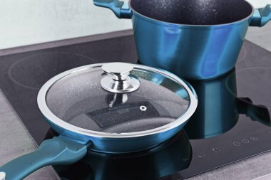 Frying pan and steel pot on modern induction cooktop. clipart