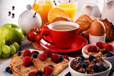 Kahvaltının yanında kahve, portakal suyu, kruvasan, yumurta, mısır gevreği ve meyve var. Dengeli diyet.