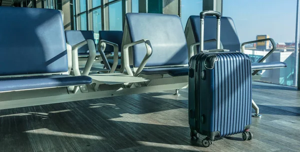 Small plastic travel suitcase in the airport hall.