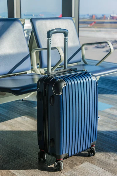 Small plastic travel suitcase in the airport hall.