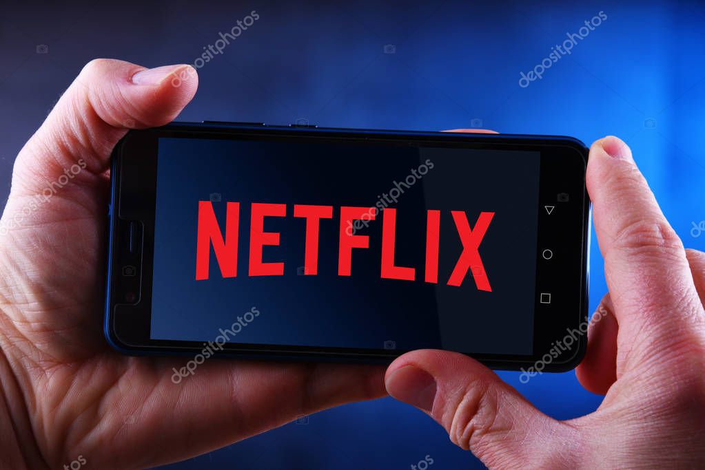 POZNAN, POL - MAR 24, 2019: Hands holding smartphone displaying logo of Netflix, an American media-services provider headquartered in Los Gatos, California, USA