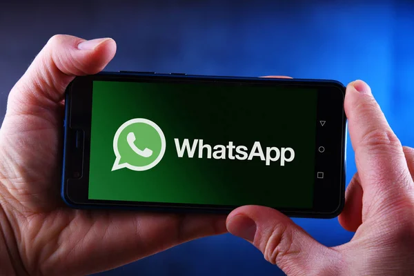 Mains tenant smartphone affichant le logo de WhatsApp Messenger — Photo