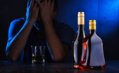 Alkol dolu şişeler ve sarhoş bir adam figürü.