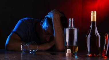 Alkol dolu şişeler ve sarhoş bir adam figürü.