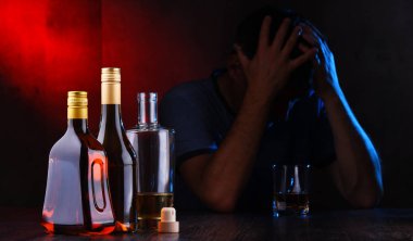 Alkol dolu şişeler ve sarhoş bir adam figürü.